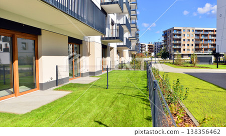 The garden of a modern residential building with a green lawn and a place to relax. Home garden. The garden of a modern residential building with a green lawn and a place to relax. Home garden. 138356462