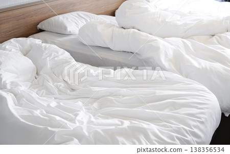 A hotel room immediately after check-out: clean white linens and a wrinkled down comforter. A hotel room immediately after check-out: clean white linens and a wrinkled down comforter. 138356534