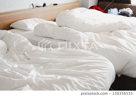 A realistic bedroom scene after waking up, before making the bed: pleasant morning light and a soft down comforter. 138356535