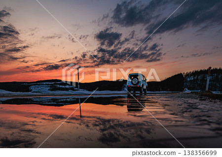 A winter sunset and a 4x4 vehicle reflected in the water create a fantastical reflection scene. 138356699