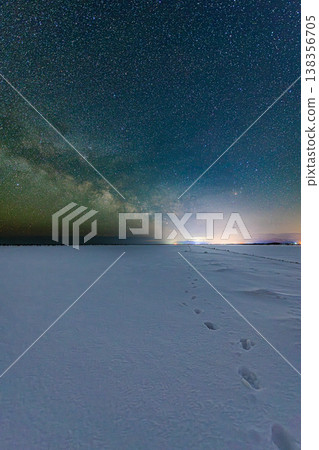 A breathtaking view of the Milky Way stretching across a snow-covered landscape on a starry winter night. 138356705