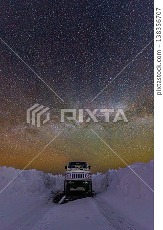 A winter road running through the starry sky and the Milky Way, a fantastical scene of snow walls and cars. 138356707