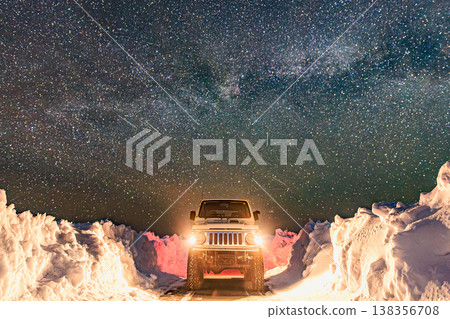 A night view of an off-road vehicle standing on a snowy road, with a sky full of stars and the Milky Way. A night view of an off-road vehicle standing on a snowy road, with a sky full of stars and the Milky Way. 138356708