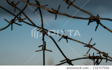 Wire fence stands against a blue sky and clouds in a rural area at dusk Wire fence stands against a blue sky and clouds in a rural area at dusk 138357090