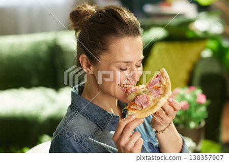 Smiling Woman with Pizza Slice in Cozy Living Room Smiling Woman with Pizza Slice in Cozy Living Room 138357907