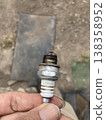 Holding a deteriorated spark plug from farm equipment by hand - Maintenance photo 138358952