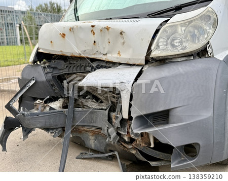This minibus was significantly damaged as a result of a serious head-on collision. A seriously damaged grey minibus, which shows significant collision marks in the front and extensive rust marks. This minibus was significantly damaged as a result of a serious head-on collision. A seriously damaged grey minibus, which shows significant collision marks in the front and extensive rust marks. 138359210
