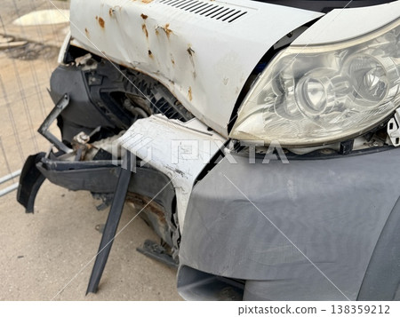 This minibus was significantly damaged as a result of a serious head-on collision. A seriously damaged grey minibus, which shows significant collision marks in the front and extensive rust marks. 138359212