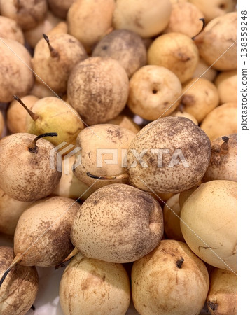 A pile of ripe juicy white desert-colored pears in a box, put up for sale at a supermarket vegetable stand, demonstrates organic, vegetarian and healthy food. Close-up. A pile of ripe juicy white desert-colored pears in a box, put up for sale at a supermarket vegetable stand, demonstrates organic, vegetarian and healthy food. Close-up. 138359248