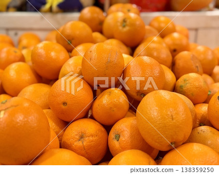 A box of ripe, fresh yellow oranges is for sale on the shelf of a fruit supermarket. Close-up. A box of ripe, fresh yellow oranges is for sale on the shelf of a fruit supermarket. Close-up. 138359250