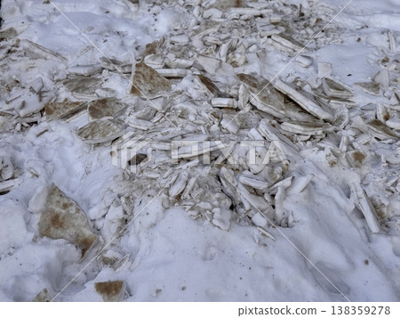 A pile of shattered ice pieces is scattered on a snowcovered ground, showcasing winters unique and beautiful textures. A pile of shattered ice pieces is scattered on a snowcovered ground, showcasing winters unique and beautiful textures. 138359278