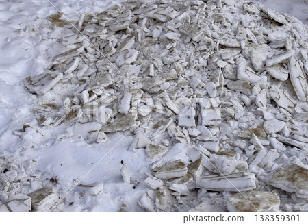 A pile of shattered ice pieces is scattered on a snowcovered ground, showcasing winters unique and beautiful textures. 138359301