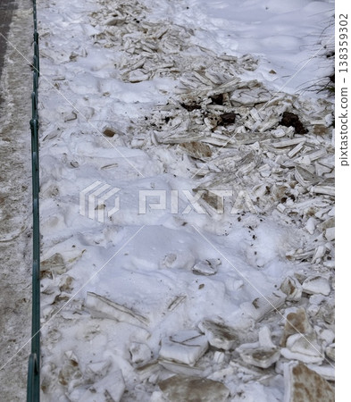A pile of shattered ice pieces is scattered on a snowcovered ground, showcasing winters unique and beautiful textures. 138359302