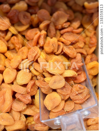 Lots of delicious plump golden orange dried apricots piled up on a tray for sale in a supermarket. Close-up. Lots of delicious plump golden orange dried apricots piled up on a tray for sale in a supermarket. Close-up. 138359313