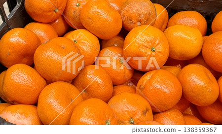 Box with ripe fresh organic tangerines on the shelf of a fruit supermarket are displayed for sale. Close-up Box with ripe fresh organic tangerines on the shelf of a fruit supermarket are displayed for sale. Close-up 138359367