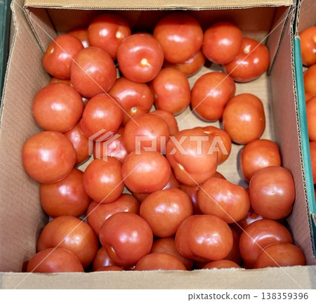 A vibrant display of ripe cherry tomatoes stacked neatly in a green basket at a bustling local market. Close-up. 138359396