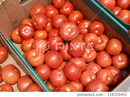 A vibrant display of ripe cherry tomatoes stacked neatly in a green basket at a bustling local market. Close-up. A vibrant display of ripe cherry tomatoes stacked neatly in a green basket at a bustling local market. Close-up. 138359401