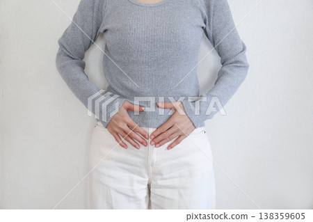 Title: Woman clutching her abdomen due to stomach pain 138359605
