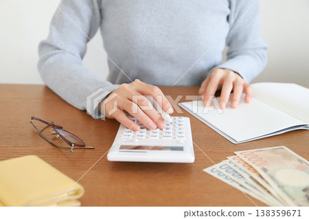 A woman's hands as she uses a calculator A woman's hands as she uses a calculator 138359671