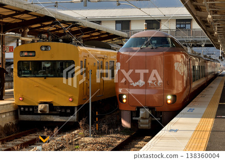 115 series trains and 273 series Limited Express Yakumo No. 1 side-by-side on the Hakubi Line 138360004