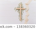 Wooden cross symbolizing christian faith and spirituality, delicate ribbon, and white gypsophila flowers on a clean copy space background remembrance for easter 138360320