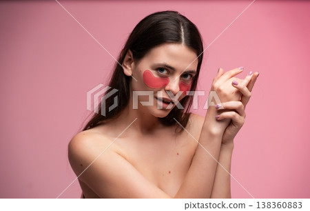 Young woman applying pink hydrating eye patches for skincare and self-care routine, enjoying pampering and beauty treatment on a vibrant pink background Young woman applying pink hydrating eye patches for skincare and self-care routine, enjoying pampering and beauty treatment on a vibrant pink background 138360883