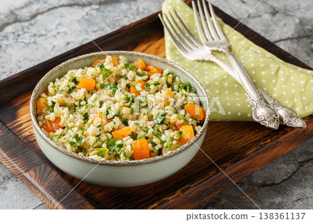 Low-calorie dietary bulgur with parsley and dried apricots close-up in a bow. Horizontal Low-calorie dietary bulgur with parsley and dried apricots close-up in a bow. Horizontal 138361137