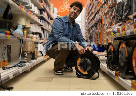 Man holding a power cable reel, choosing electrical supplies in a retail hardware store 138361162