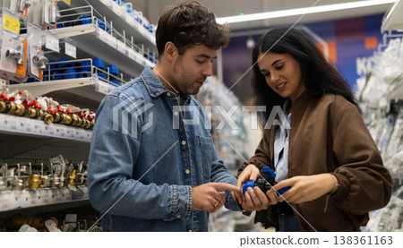 Couple discussing plumbing supplies in a hardware store aisle Couple discussing plumbing supplies in a hardware store aisle 138361163