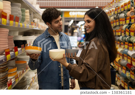 Young couple choosing different bowls for their home in a department store or supermarket aisle Young couple choosing different bowls for their home in a department store or supermarket aisle 138361181