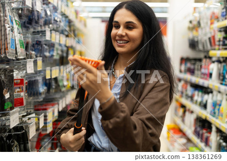 Woman examining a cleaning brush for cars in an automotive products aisle Woman examining a cleaning brush for cars in an automotive products aisle 138361269