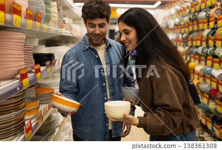 Happy couple smiling and selecting ceramic bowls for their home while shopping Happy couple smiling and selecting ceramic bowls for their home while shopping 138361309
