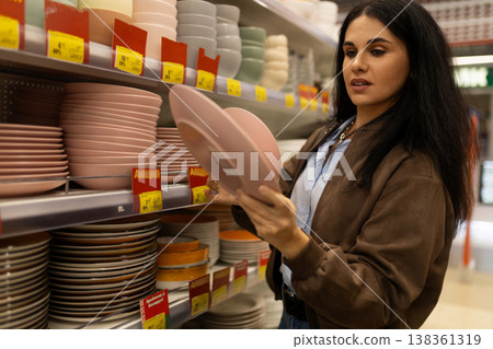 Woman choosing plates and bowls for home in a retail store Woman choosing plates and bowls for home in a retail store 138361319
