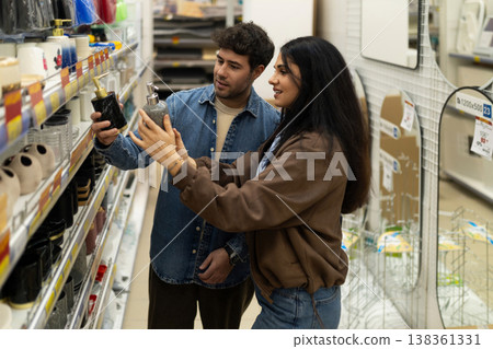 Couple comparing soap dispensers, making household purchase decisions in a retail aisle Couple comparing soap dispensers, making household purchase decisions in a retail aisle 138361331