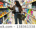 Woman shopping in a grocery store aisle, choosing products with a basket 138361338