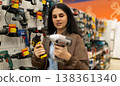 Woman choosing between power drills in a hardware store 138361340