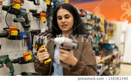 Woman choosing between power drills in a hardware store 138361340