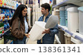 Couple smiling, choosing a trash can while shopping for household goods 138361341
