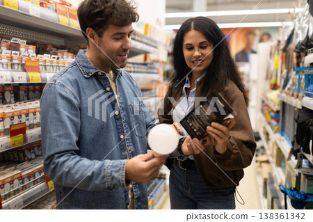 Couple comparing light bulbs, making a purchase decision in a retail aisle Couple comparing light bulbs, making a purchase decision in a retail aisle 138361342