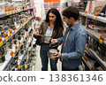 Young couple comparing stainless steel pots and selecting kitchen utensils at a store 138361346