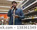 Man talking on smartphone holding a valve, shopping for plumbing supplies in a hardware store 138361349