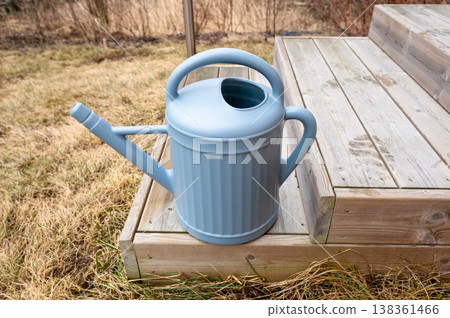 Blue watering can on wooden garden steps outdoor spring gardening equipment close up 138361466