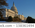 Last beams of golden sunlight on the United States Capitol Building in Washington, DC, with the American flag waving, blue sky backrgound 138361494