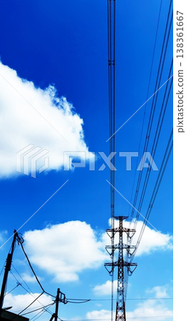 A low-angle shot of high-voltage power lines and transmission towers against a backdrop of blue sky and cumulonimbus clouds. A low-angle shot of high-voltage power lines and transmission towers against a backdrop of blue sky and cumulonimbus clouds. 138361667