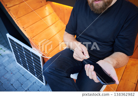 Cropped view of man connecting smartphone to photovoltaic solar panel. Integration of sustainable renewable energy into everyday life, demonstrating practical use of solar power for charging devices. Cropped view of man connecting smartphone to photovoltaic solar panel. Integration of sustainable renewable energy into everyday life, demonstrating practical use of solar power for charging devices. 138362982