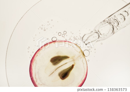 Pipette dropping clear liquid onto translucent grape slice, showcasing natural skincare ingredients 138363573