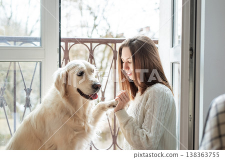 Woman training golden retriever dog holding paw indoors 138363755