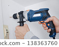 close view of a man drilling a hole in a wall 138363760