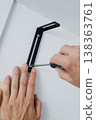 a man fastening a screw in a wall bracket 138363761