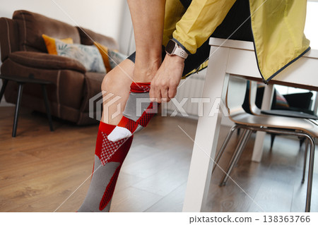 a man pulls up a compression sock at home a man pulls up a compression sock at home 138363766